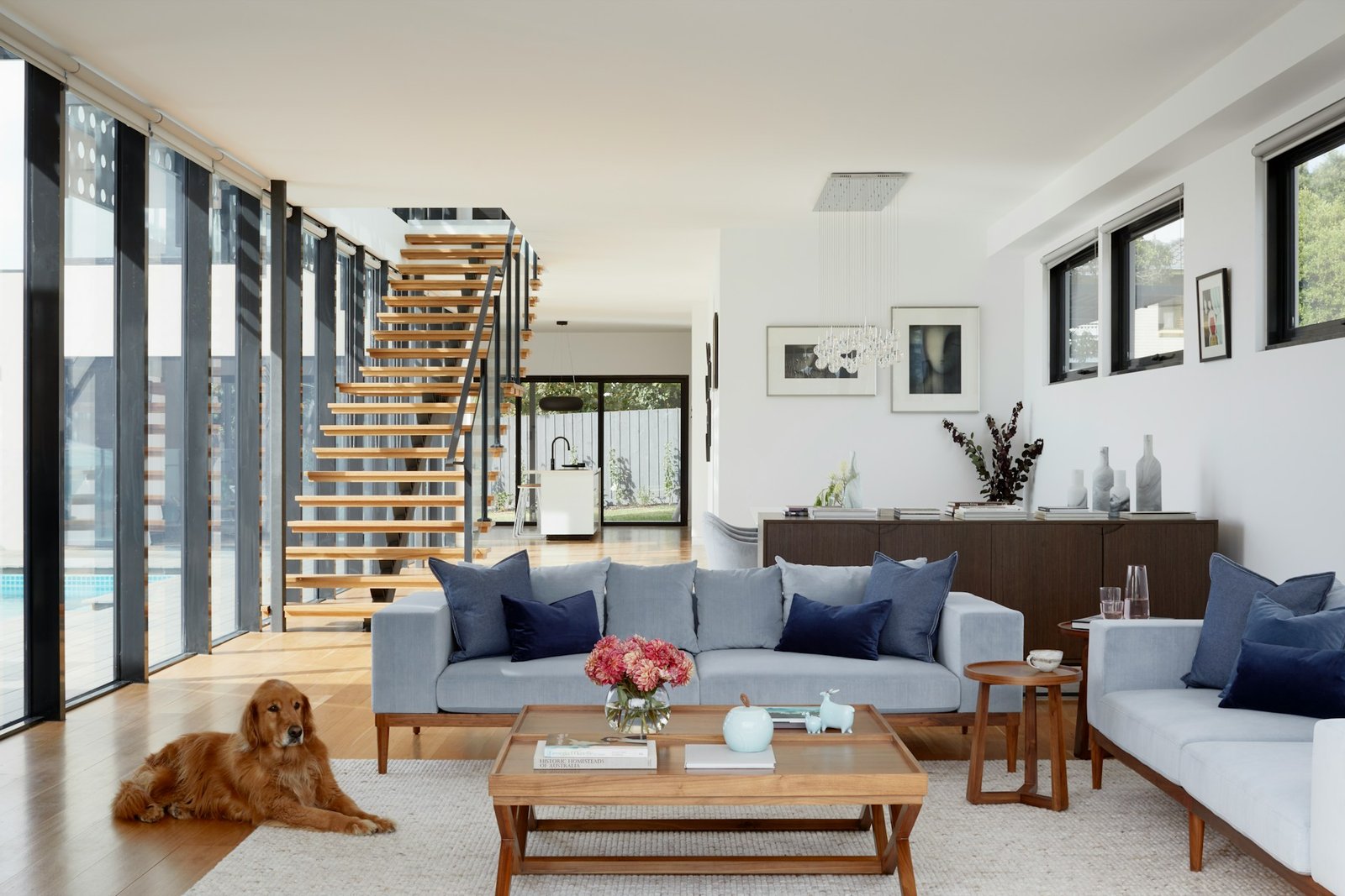 Modern loungeroom with wooden stairs leading up and golden retriever lying down